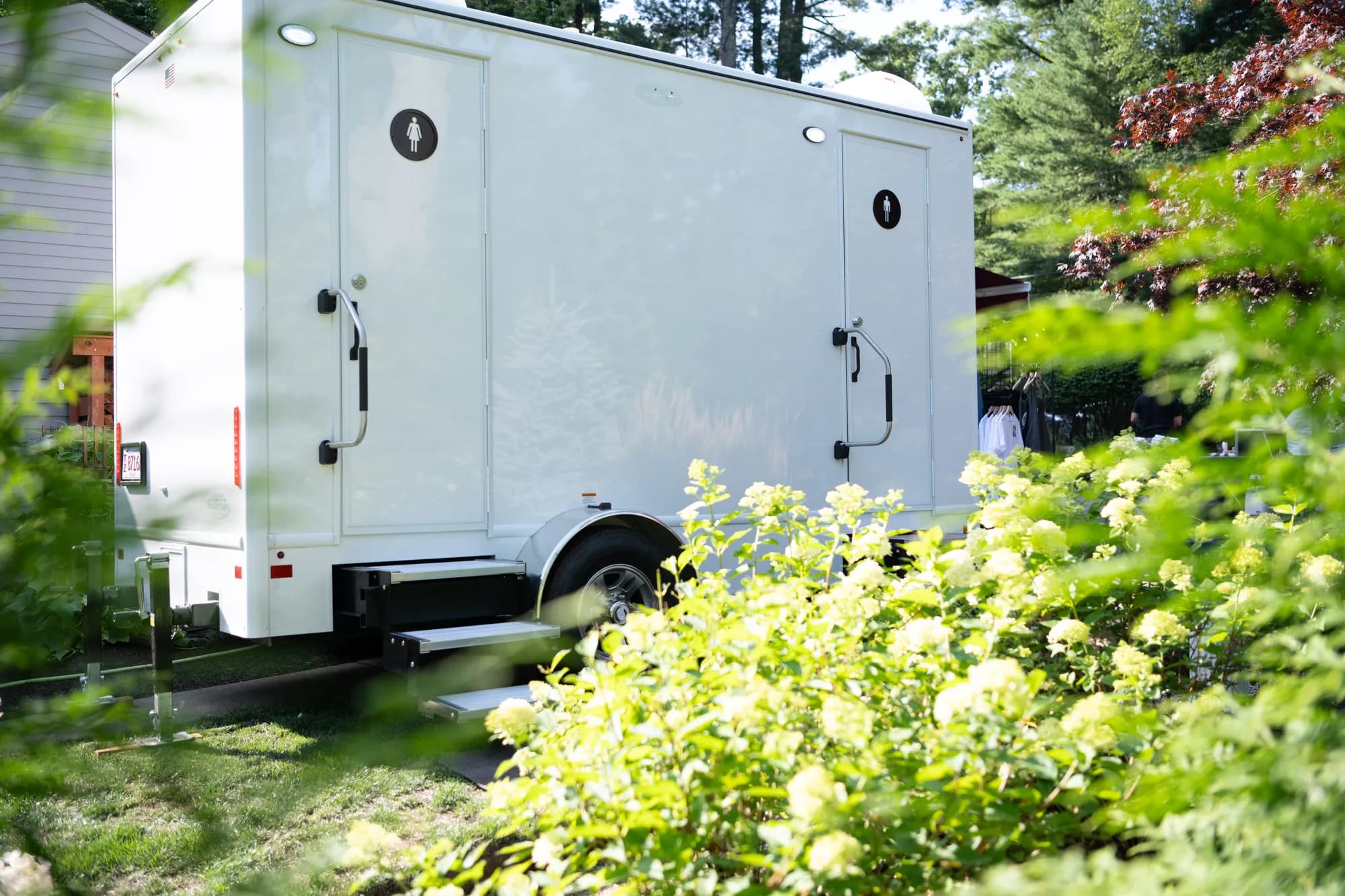 Elite Event Solutions restroom trailer parked in a landscaped garden for a backyard wedding in Massachusetts